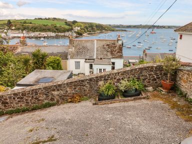 A sloped outdoor area with stone walls potted plants and a view of houses and a harbor with boats at Seabien in Falmouth