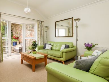 A living room with green sofas wooden coffee table and lamps by a window at Seabien in Falmouth