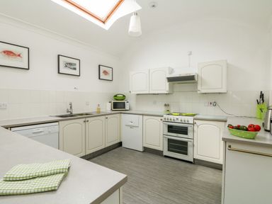 A kitchen with white cabinets a stove a microwave a dishwasher and a skylight at Seabien in Falmouth