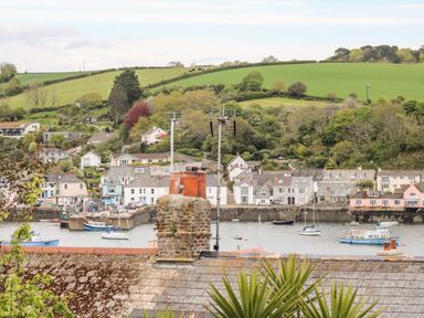 A harbor with boats docked near houses and green fields on a hillside at Seabien in Falmouth