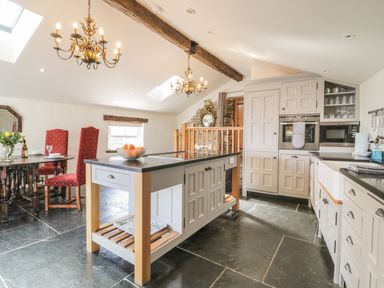 A kitchen with an island and dining table with red chairs at Glanville House in Mevagissey