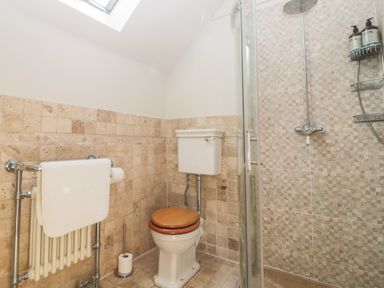 A bathroom with a toilet a towel rack and a shower at Glanville House in Mevagissey