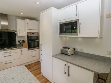 A kitchen with cabinets, a microwave, and a toaster at Glebe House in Bigbury