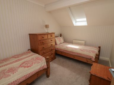 A bedroom with twin beds and a dresser at Glebe House in Bigbury