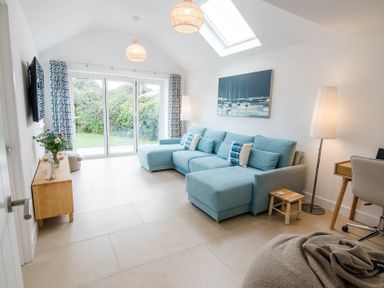 A living room with a blue sofa and glass door at Lanesend in St Agnes