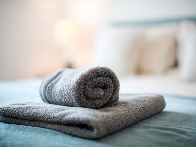 A towel rolled on a bed at Lanesend in St Agnes