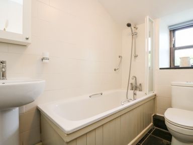 A bathroom with a bathtub shower combination a sink and a toilet at Gurnard's Cottage in St Ives