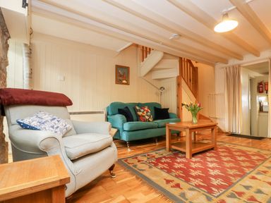 A living room with two sofas a wooden coffee table and a patterned rug at Gurnard's Cottage in St Ives