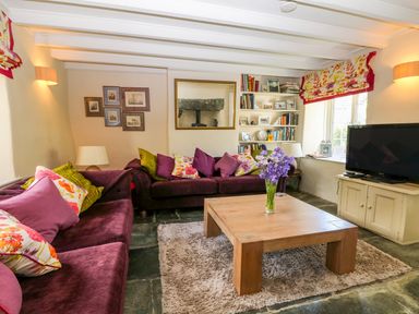 A living room with purple sofas a wooden coffee table and a television at Parwin in Tintagel