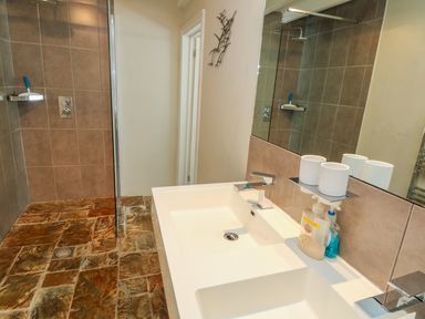 A bathroom with a white sink countertop and a walk-in shower with brown tiles at Parwin in Tintagel