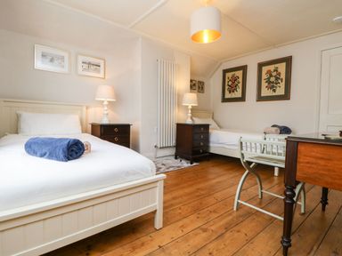 A bedroom with two single beds bedside tables lamps and framed pictures on walls at Parwin in Tintagel