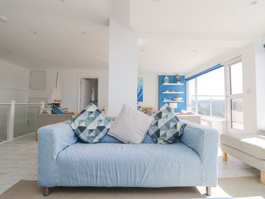 A living room with a blue sofa and patterned cushions at St Ives View in Porthtowan