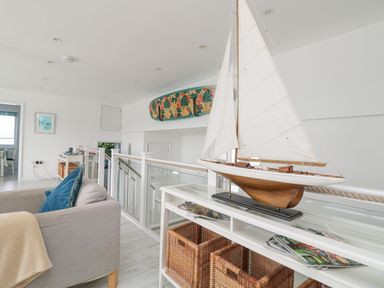 A sitting area with a model sailboat on a white table and a sofa with blue cushions at St Ives View in Porthtowan