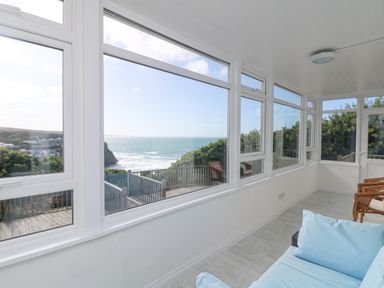 A sunroom with large windows overlooking the sea at St Ives View in Porthtowan