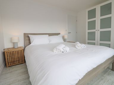 A bedroom with a bed and rolled towels on top at St Ives View in Porthtowan
