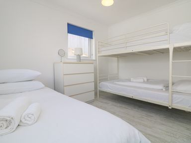 A bedroom with a single bed with towels a bunk bed and a chest of drawers with a lamp at St Ives View in Porthtowan