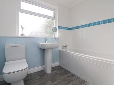 A bathroom with a toilet sink and bathtub with blue and white tiles at St Ives View in Porthtowan