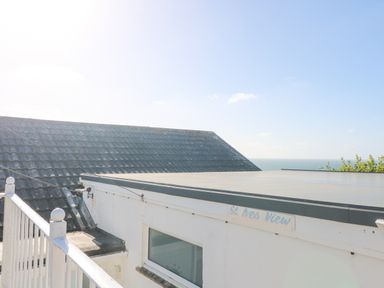 A view of rooftops with a sign reading St Ives View and the sea in the background at Porthtowan