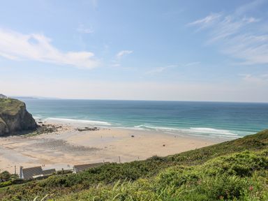 A sandy beach with cliffs and greenery overlooking the sea at St Ives View in Porthtowan