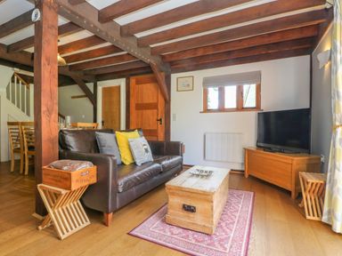 A living room with a leather sofa coffee table television and wooden beams at Oaklands Near Boscastle