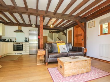 An open plan living area with a leather sofa and wooden coffee table near a kitchen and dining table at Oaklands Near Boscastle