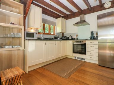 A kitchen with wooden beams a stainless steel refrigerator oven microwave and glass cabinet at Oaklands Near Boscastle
