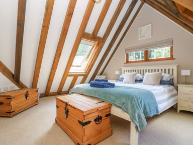 A bedroom with a double bed wooden chests bedside tables and exposed ceiling beams at Oaklands Near Boscastle