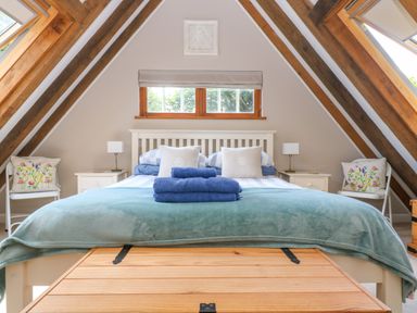 A bedroom with a double bed and blue towels on it beneath a small window in an attic room at Oaklands Near Boscastle