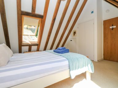 A bedroom with a bed striped bedding and folded towels under a skylight window at Oaklands Near Boscastle