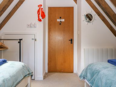 A bedroom with two single beds covered with light blue blankets and a wooden door between them Oaklands Near Boscastle