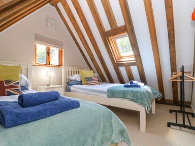 A bedroom with two single beds and wooden ceiling beams at Oaklands Near Boscastle