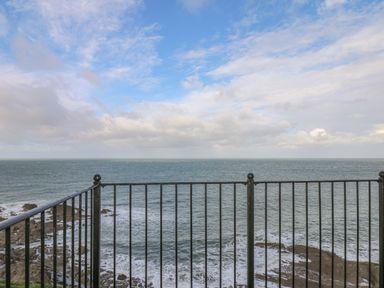 A view of the ocean and rocky shore from behind a black metal railing at Seasiders in Ilfracombe