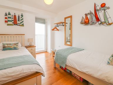 A bedroom with two single beds a nightstand and wall decorations at Seasiders in Ilfracombe