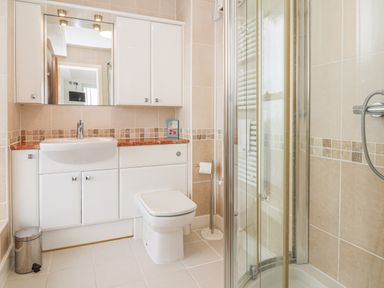 A bathroom with a sink cabinet mirror toilet shower and tiled walls at Seasiders in Ilfracombe