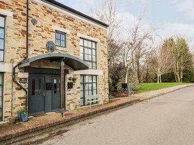 A two-door entrance with stone walls next to a paved road and trees at Riverview in Lostwithiel