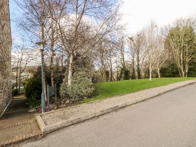 A paved pathway beside a stone building with trees and a grassy area at Riverview in Lostwithiel