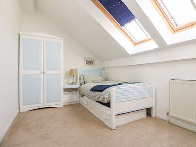 A bedroom with a single bed bedside table and wardrobe under sloped ceiling skylights at Riverview in Lostwithiel