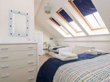 A bedroom with two single beds a chest of drawers a wardrobe and three skylight windows with star patterned blinds at Riverview in Lostwithiel