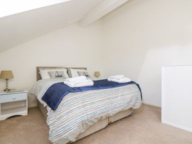 A bedroom with a bed with striped bedding and pillows a bedside table with a lamp at Riverview in Lostwithiel