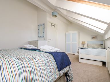 A bedroom with two single beds a wardrobe a chest of drawers and a wall mirror at Riverview in Lostwithiel