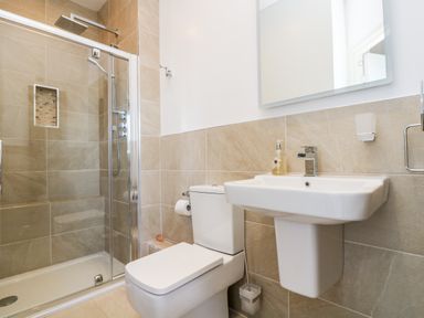 A bathroom with a shower enclosure toilet and wall-mounted sink at Riverview in Lostwithiel