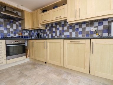A kitchen with light wood cabinets a tiled backsplash and an oven at Riverview in Lostwithiel