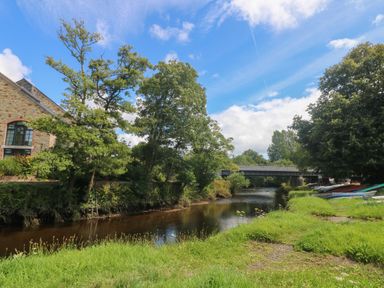 A river with trees along the bank and a bridge crossing over the water at Riverview in Lostwithiel