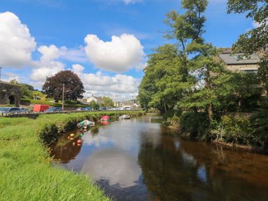 A river with boats along the bank and trees by houses in a village at Riverview in Lostwithiel