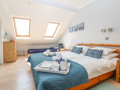 A bedroom with a double bed and single bed under skylight windows at Tides in Padstow