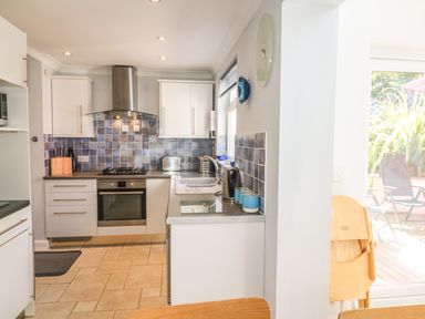 A kitchen with white cabinets blue tile backsplash and stainless steel appliances at Tides Padstow