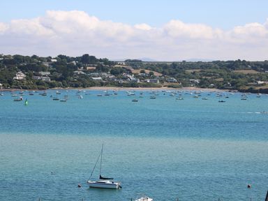 A coastal scene with numerous boats on the water and houses along the shoreline at Tides in Padstow
