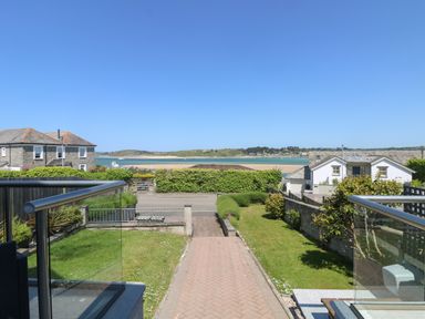 Front garden with a pathway leading to a road and a view of a beach and houses at Tides in Padstow