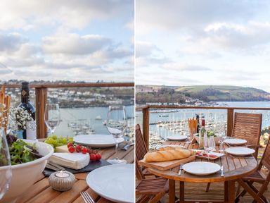 A wooden outdoor dining table set with plates wine glasses bread salad and cheese overlooking a marina at Totherside in Kingswear