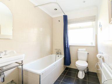 A bathroom with a bathtub shower toilet and sink at Seaport Lodge in Mawgan Porth